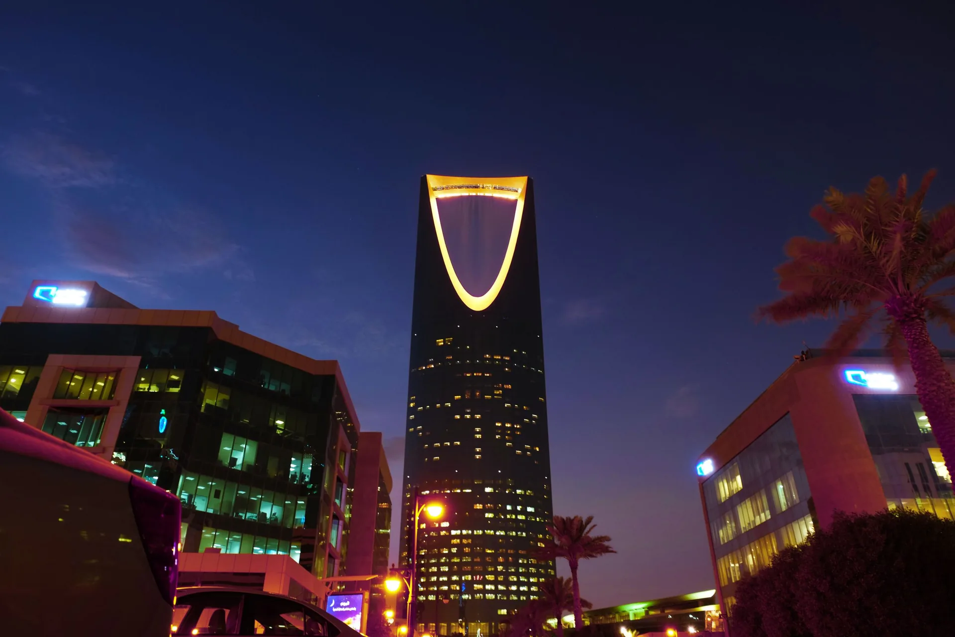 A modern city skyline at night, its towers and offices brightly lit.